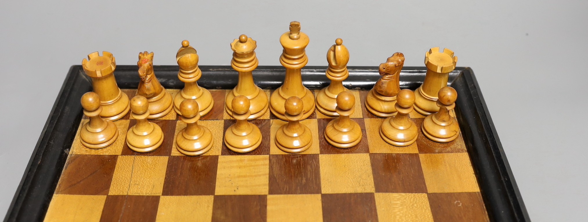 A late 19th / early 20th century weighted Staunton chess set, red crown stamps, kings 7.5cm, with inlaid chess board 32cm